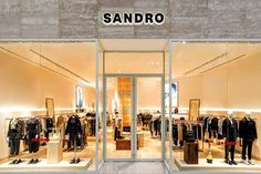 a store front with clothes on display in the window and lights above it that says sandro