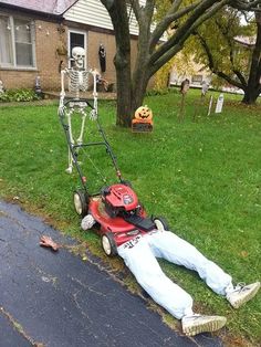 a man laying on the ground in front of a lawn mower with a skeleton attached to it