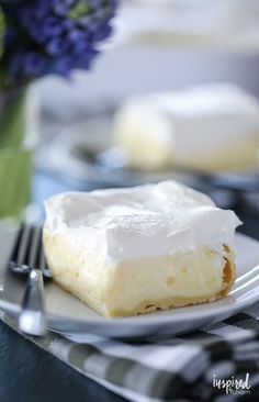 a piece of cake sitting on top of a white plate next to a vase with purple flowers