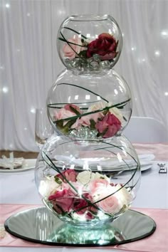 three glass vases filled with flowers sitting on top of a pink table cloth covered table