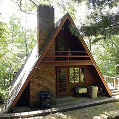 a - frame cabin in the woods surrounded by trees