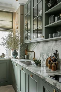 a kitchen with green cabinets and white marble counter tops, along with an open window