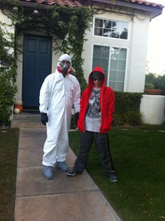 two people in costumes are standing on the sidewalk near a house with a blue door