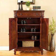 a wooden cabinet with shoes on it and a mirror in the corner next to it