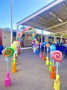 an outdoor area with balloons and candy canes in the shape of spirals on poles