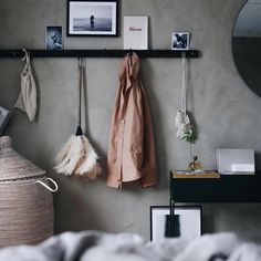 there is a coat rack with two coats hanging on the wall next to a bed