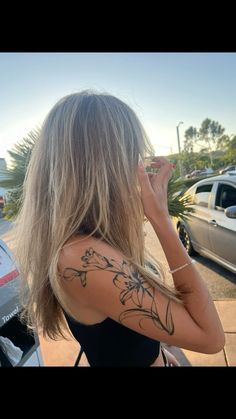 a woman with tattoos on her back standing next to a car