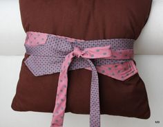 a pillow with a pink ribbon tied around it on a white couch cushion that is covered in brown and pink polka dot fabric