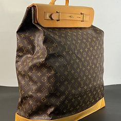 Large travel bag from the world-renowned Louis Vuitton. Crafted with meticulous attention to detail, this exquisite piece features the iconic Monogram canvas adorned with sumptuous tan cowhide leather accents, exuding sophistication and timeless elegance.  A testament to Louis Vuitton's legacy of exceptional design, this steamer bag sac showcases a near-perfect condition despite its age, reflecting the brand's commitment to quality craftsmanship. This large canvas and leather travel companion, n High-end Travel Backpack Shoulder Bag, Designer Travel Bags In Coated Canvas, Luxury Coated Canvas Backpack With Leather Handles, Luxury Backpack With Leather Handles And Coated Canvas, Designer Travel Tote Backpack, Designer Bags With Leather Lining And Monogram Canvas, Designer Monogram Canvas Bag With Leather Lining, Designer Coated Canvas Backpack With Leather Handles, Brown Monogram Canvas Rectangular Backpack