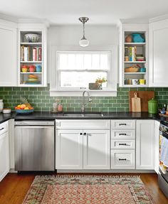 a kitchen with white cabinets and green tile backsplash, stainless steel dishwasher