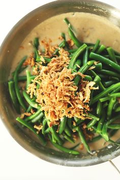 green beans with shredded parmesan cheese in a silver bowl on a white surface