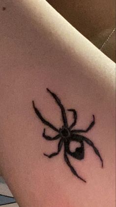 a black spider tattoo on the back of a woman's shoulder