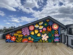 a colorful mural on the side of a building with flowers painted on it's sides