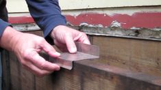 a person holding a piece of metal on top of a wooden box next to a building