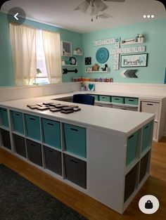 a kitchen with blue walls and white counter tops, drawers on each side and several bins in the middle