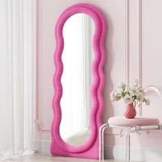 a pink mirror sitting on top of a white table next to a vase with flowers