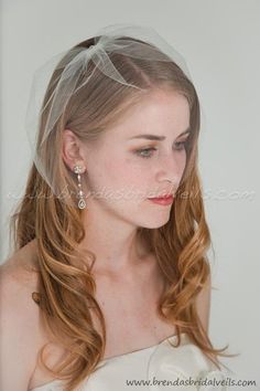 a woman wearing a veil and smiling at the camera with her hair in half up