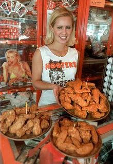 a woman standing in front of a counter filled with fried food and holding a plate full of chicken nuggets