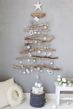 a christmas tree made out of branches with ornaments hanging from it's sides and on the wall