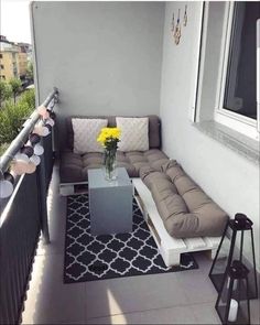 a living room filled with furniture and yellow flowers on top of a table in front of a window