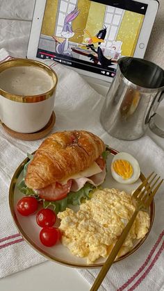 a breakfast plate with eggs, ham, tomato, and croissant on it