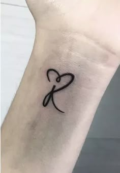 a small black heart tattoo on the wrist