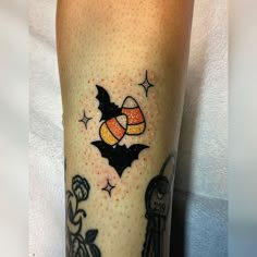 a person with a tattoo on their leg that has an image of a bat and pumpkin