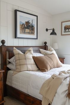 a bed with pillows and blankets on top of it next to a framed painting above the bed