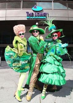 three people dressed up in costumes and hats posing for a photo outside the entrance to an arena