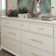 a large silver vase sitting on top of a white dresser