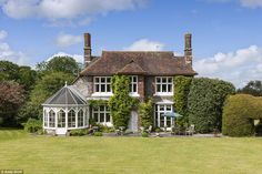 a large house that is in the middle of some grass and bushes with trees around it