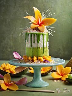 a cake with green icing and flower decorations on a blue plate next to flowers