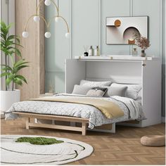 a white bed sitting next to a green plant in a bedroom on top of a hard wood floor