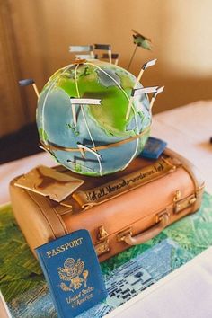 a small globe sitting on top of two suitcases with flags sticking out of it