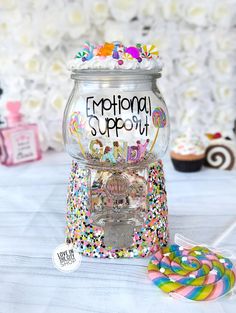 a candy dispenser sitting on top of a table next to cupcakes