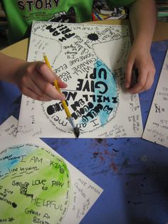 a child's hand writing on paper with colored crayons