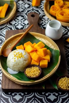 a wooden plate topped with rice, mangoes and other foods on top of a table