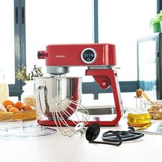 a red mixer sitting on top of a counter next to oranges and other kitchen items