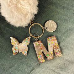 a keychain with the letter m on it and a butterfly charm attached to it