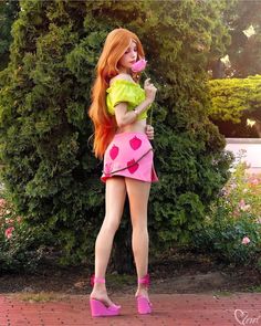 a woman with long red hair wearing pink shoes and holding a flower in her hand