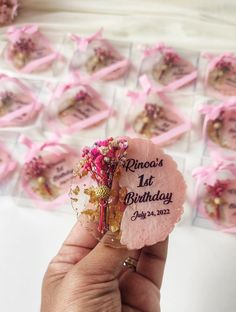 a person holding up a pink flower in front of a bunch of small tags that say princess 1st birthday