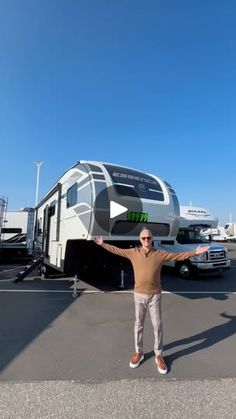 a man standing in front of an rv with his arms out and two trucks behind him