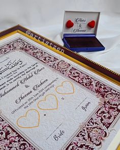 a wedding card with two hearts on it and a ring in the box next to it