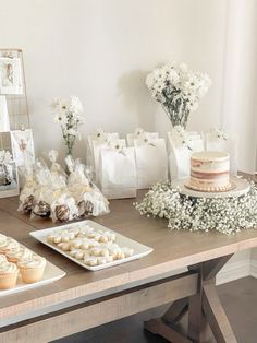 a table topped with cakes and cupcakes on top of wooden tables covered in white flowers