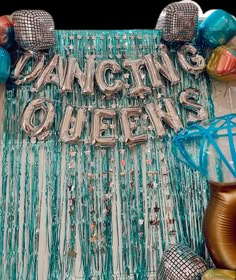 there are balloons that say dancing queen and some streamers on the table in front of them