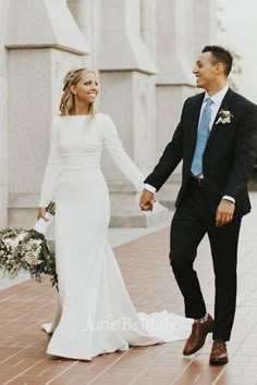 a bride and groom holding hands in front of a building with columns on either side