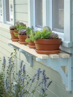 three potted plants sitting on top of a window sill in front of a house