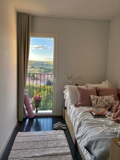 a bedroom with a bed, rugs and window overlooking the city below it on a sunny day