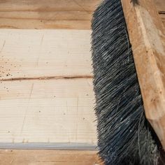 a brush sitting on top of a wooden floor next to a piece of plywood