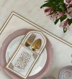 a pink and white place setting with gold accents